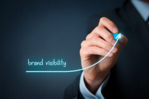 A professional sketching an upward-curving arrow with "brand visibility" on it.